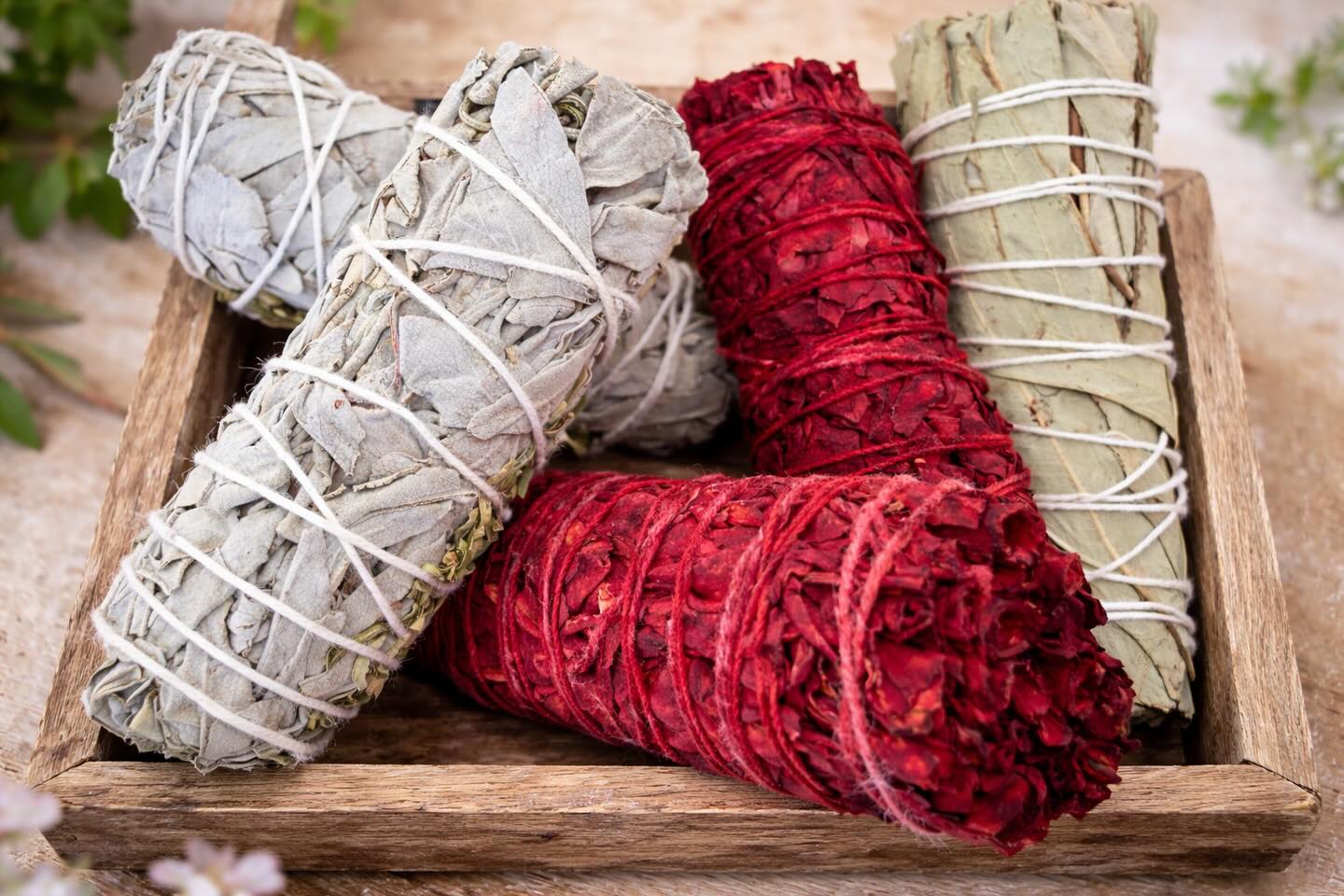 Bâtons de sauge blanche, sauge rouge et eucalyptus dans un plateau en bois